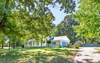 Front exterior of 831 Northpointe Drive in Mountain Home, Arkansas, with a covered porch, attached garage and mature shade trees.