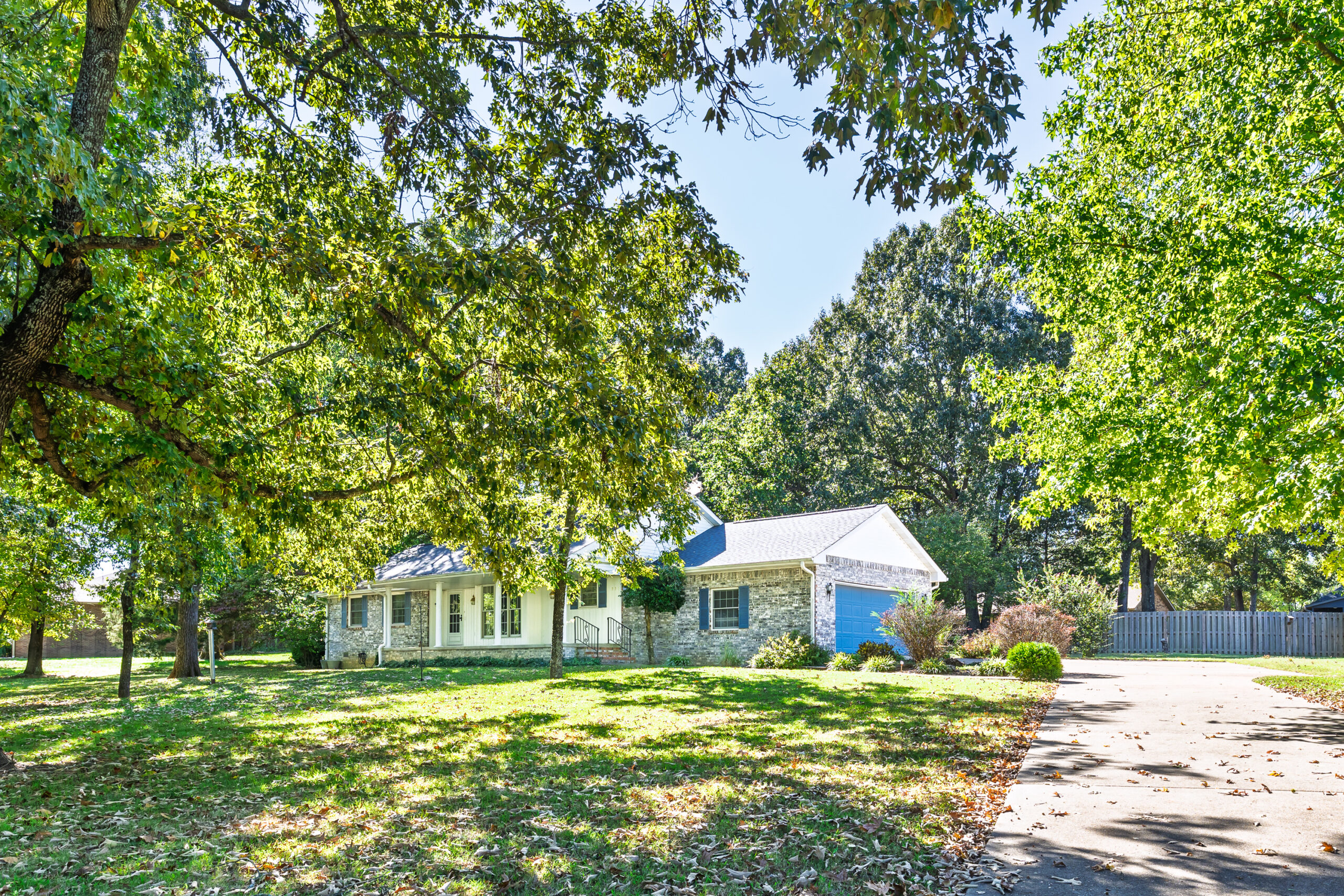 Front exterior of 831 Northpointe Drive in Mountain Home, Arkansas, with a covered porch, attached garage and mature shade trees.