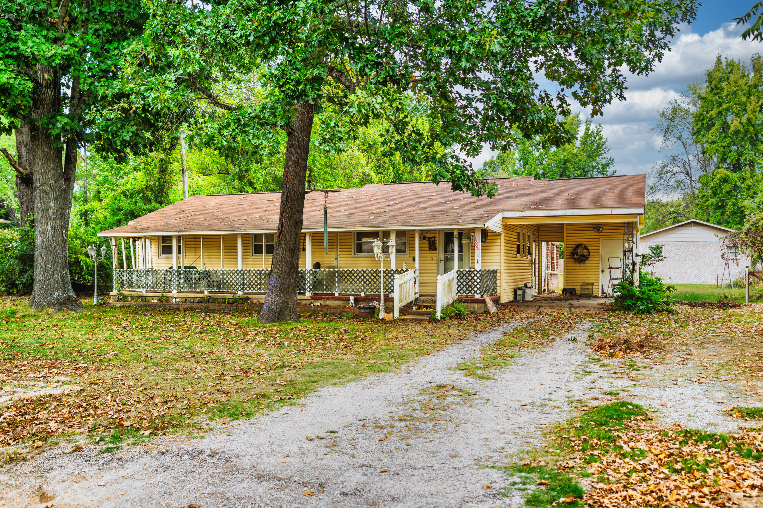 Front exterior of 809 Langston Street in Mountain Home, Arkansas, with a covered porch, attached carport and mature shade trees.