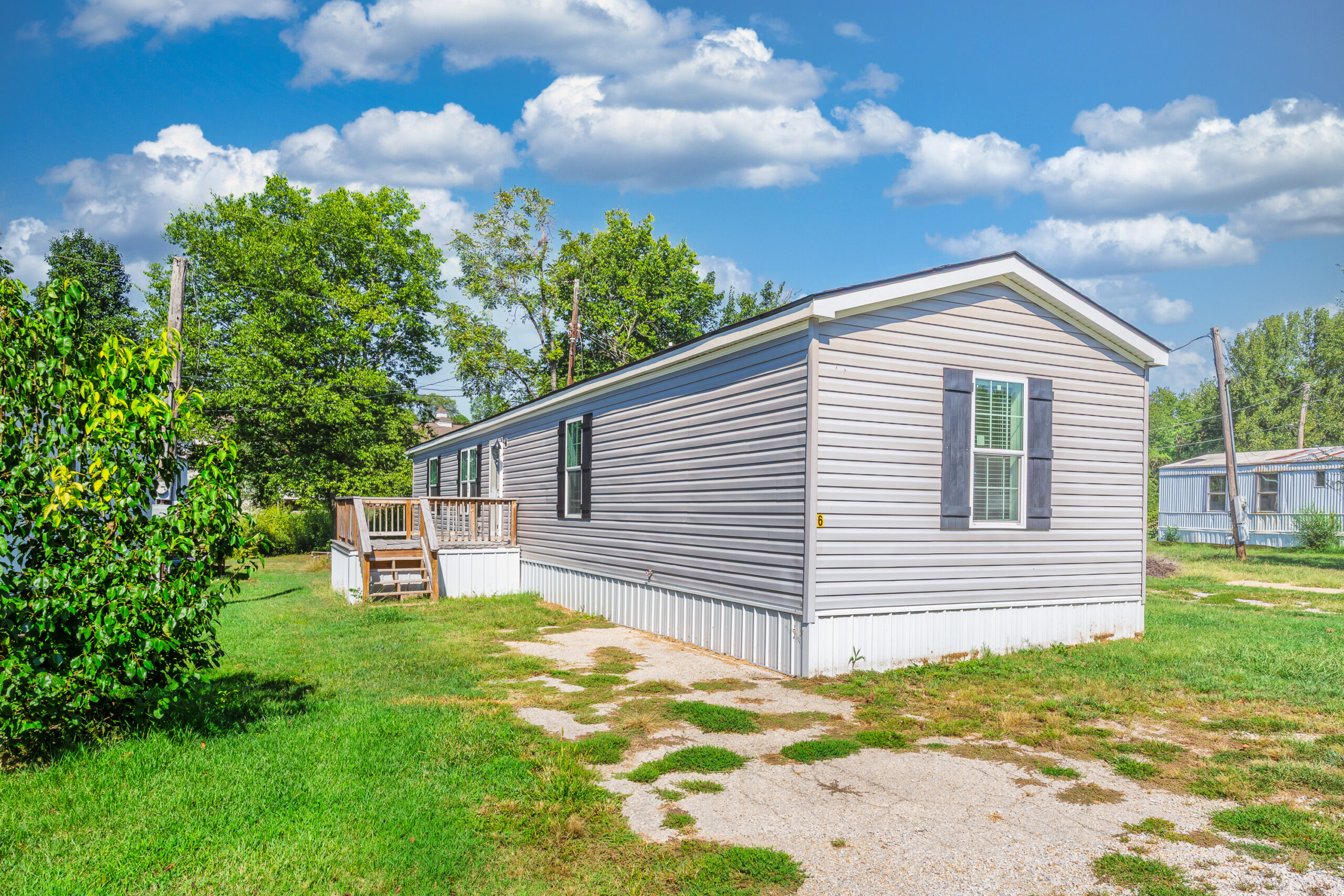 Gray manufactured home with a wooden entry deck at 1023 E. 9th Street, Lot 6, Mountain Home, Arkansas.